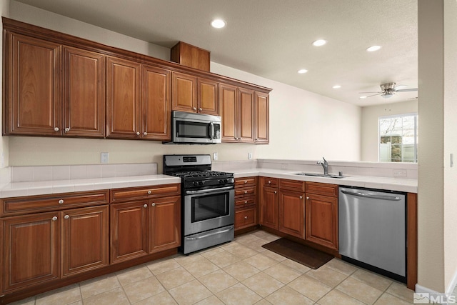 kitchen with brown cabinets, stainless steel appliances, a sink, and light countertops