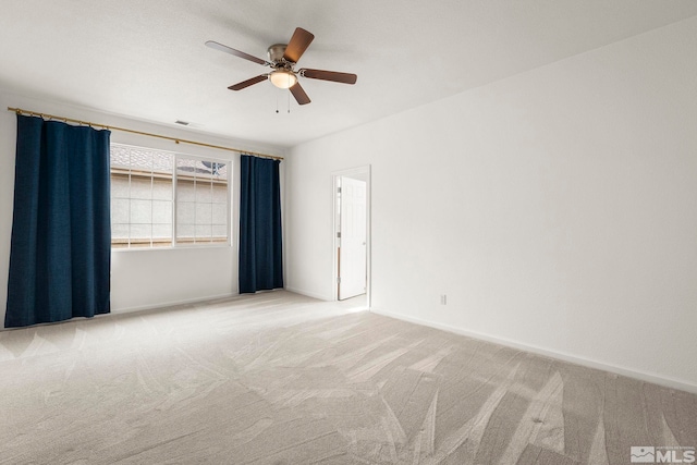 empty room featuring light carpet, baseboards, and a ceiling fan