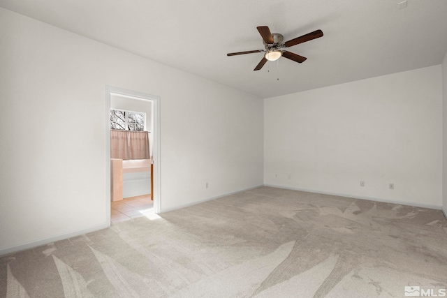 spare room with ceiling fan, baseboards, and light colored carpet