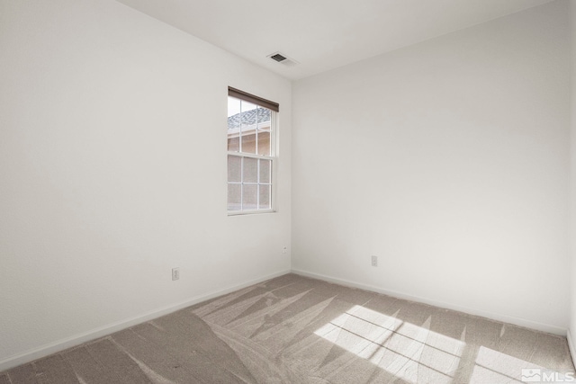 empty room with baseboards, visible vents, and light colored carpet