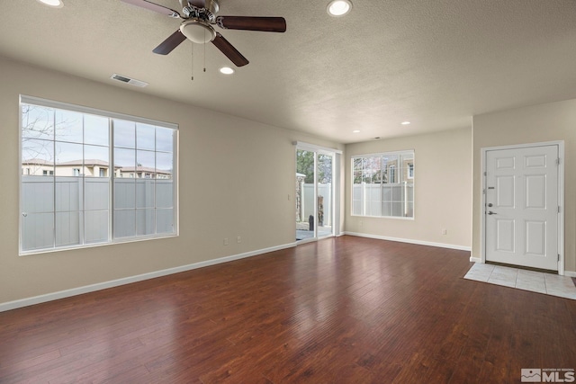 empty room with baseboards, a textured ceiling, visible vents, and wood finished floors