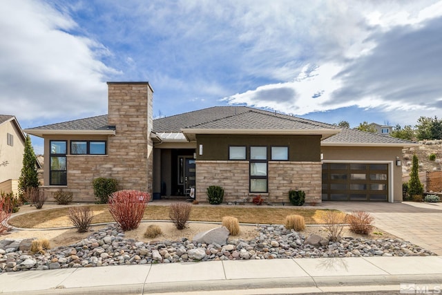 prairie-style home with a garage, driveway, stone siding, stucco siding, and a chimney