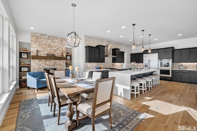 dining space featuring light wood-type flooring, a fireplace, and recessed lighting