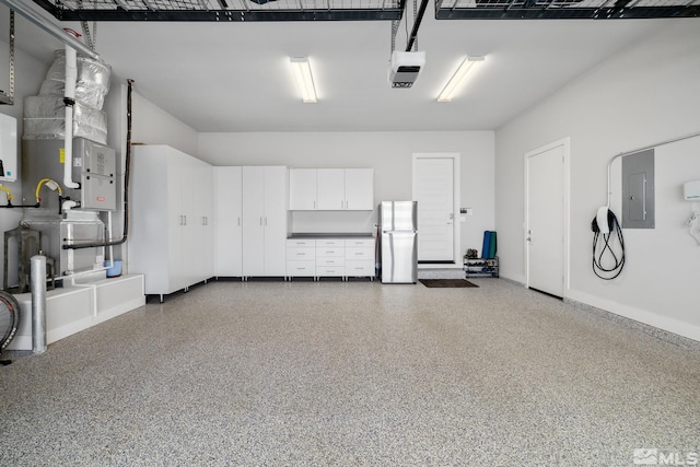 garage featuring a garage door opener, freestanding refrigerator, and electric panel