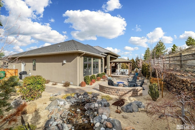 back of property featuring a patio, a fire pit, fence, a gazebo, and stucco siding