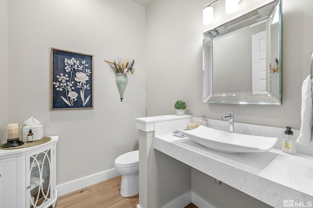 bathroom with a sink, baseboards, toilet, and wood finished floors