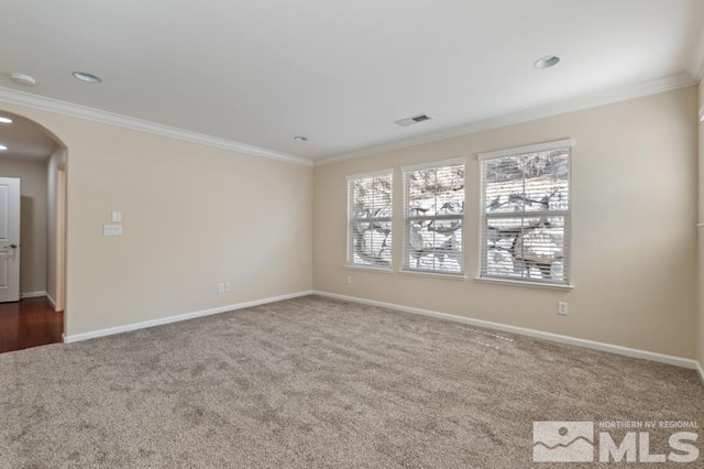 spare room featuring arched walkways, carpet flooring, visible vents, baseboards, and ornamental molding