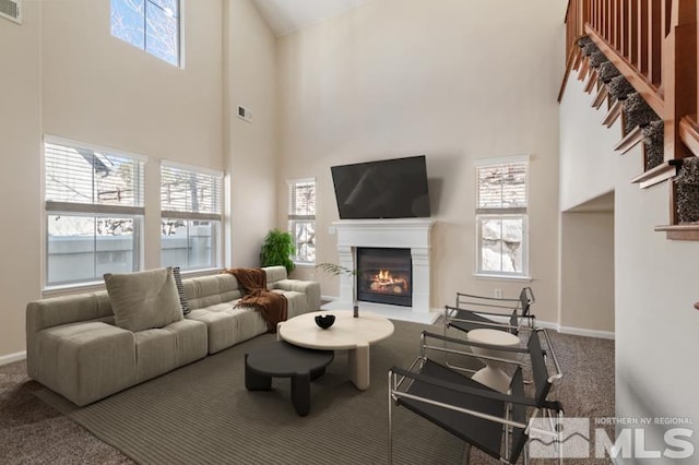 living area with a lit fireplace, carpet floors, visible vents, and baseboards