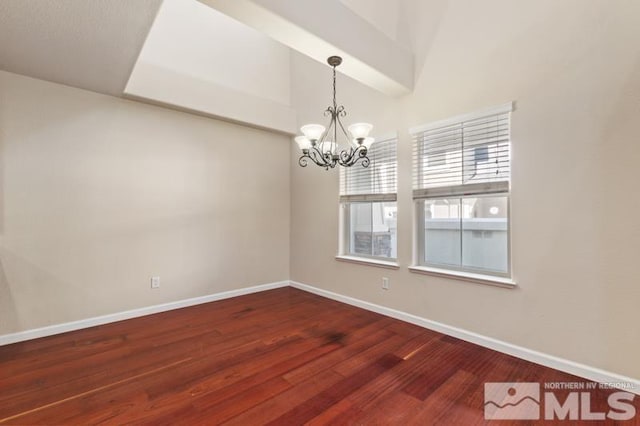 spare room featuring dark wood-type flooring, baseboards, and an inviting chandelier