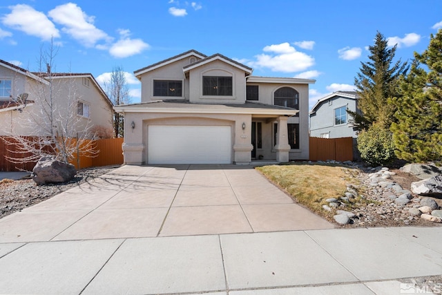 traditional-style home with driveway, an attached garage, fence, and stucco siding