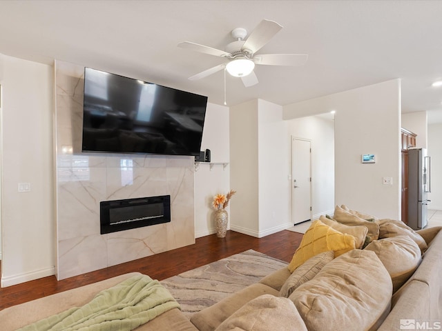 living area featuring ceiling fan, a premium fireplace, wood finished floors, and baseboards