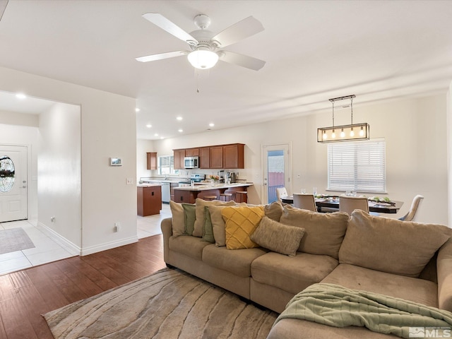 living area featuring light wood-style floors, ceiling fan, baseboards, and recessed lighting