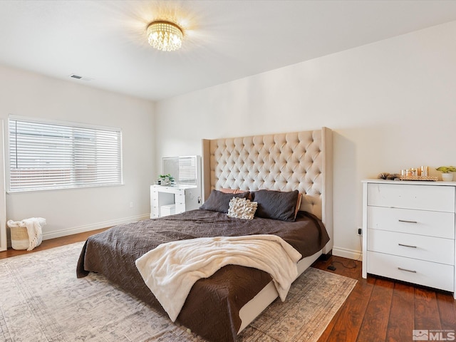 bedroom with a notable chandelier, baseboards, visible vents, and hardwood / wood-style floors