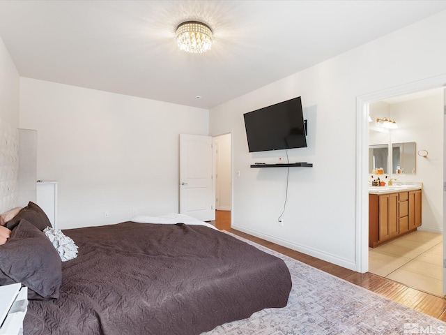 bedroom with a chandelier, light wood-type flooring, connected bathroom, and baseboards