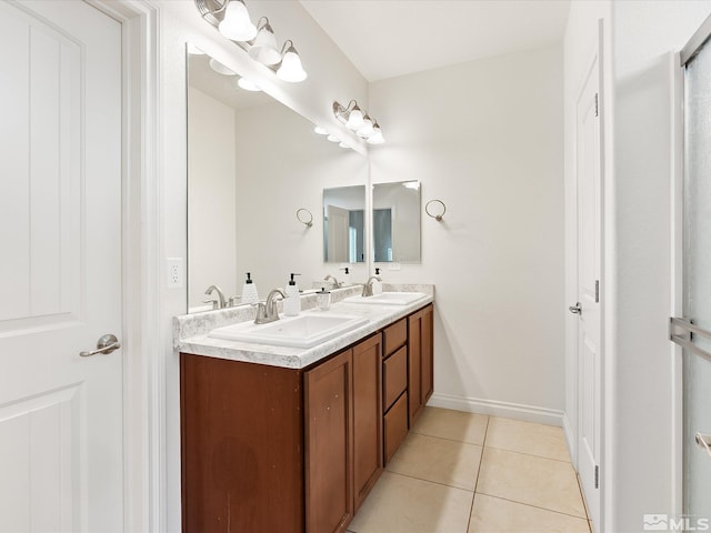 bathroom with double vanity, a sink, baseboards, and tile patterned floors