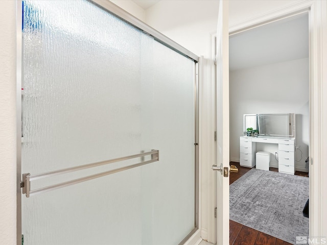 bathroom with a shower stall and wood finished floors