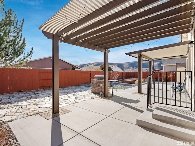 view of patio featuring a fenced backyard, a mountain view, and a pergola