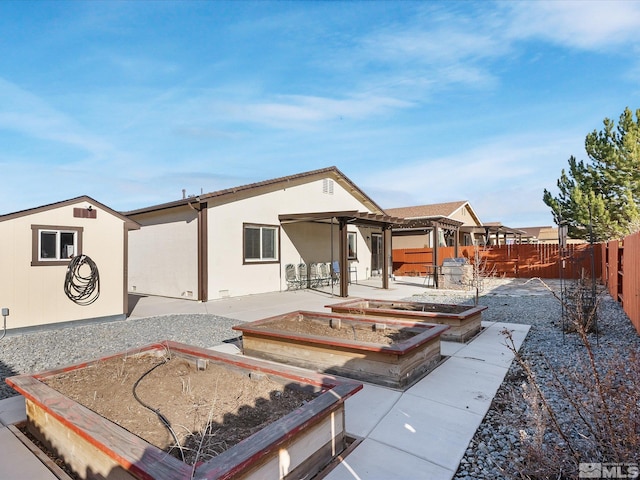 rear view of house featuring a patio, a fenced backyard, a vegetable garden, and stucco siding