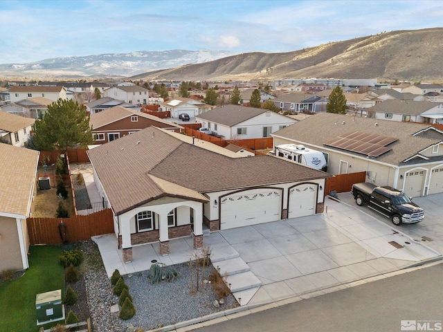 view of front of property with concrete driveway, a mountain view, fence, a garage, and a residential view