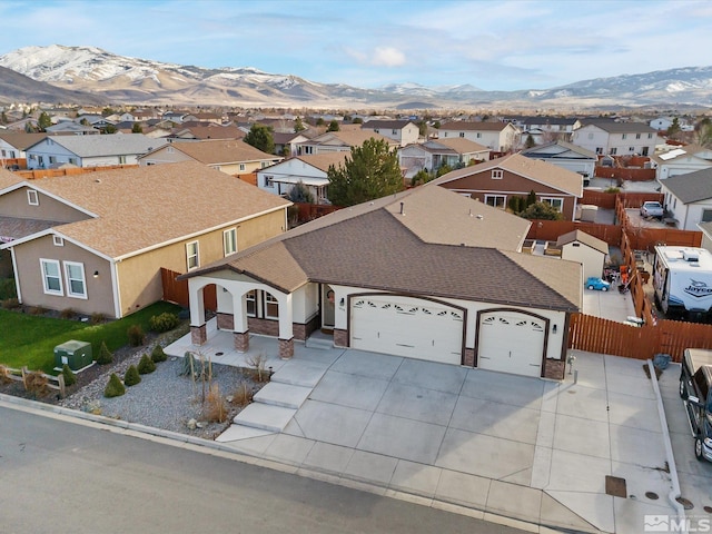 view of front facade featuring an attached garage, a residential view, fence, and a mountain view