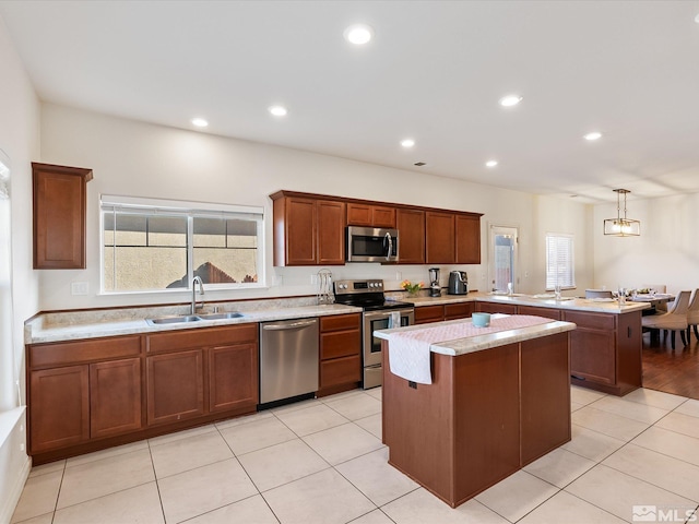 kitchen with appliances with stainless steel finishes, a sink, a kitchen island, plenty of natural light, and a peninsula