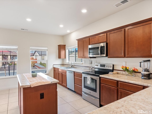 kitchen featuring stainless steel appliances, light countertops, visible vents, a sink, and a kitchen island