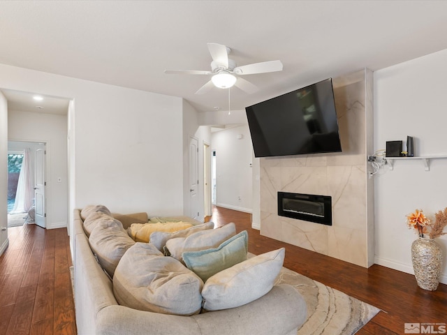 living area with hardwood / wood-style flooring, ceiling fan, a premium fireplace, and baseboards