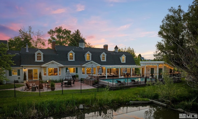 back of house at dusk featuring a yard, a fenced in pool, a patio, and fence