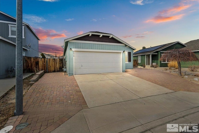 view of front of house with driveway, an attached garage, fence, and an outdoor structure