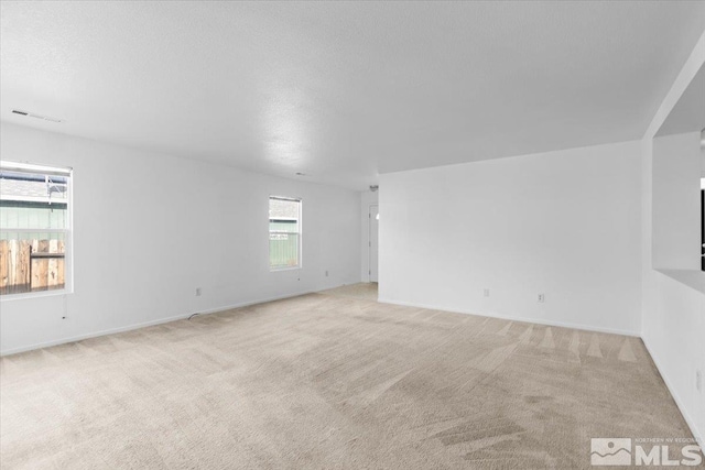 carpeted spare room featuring a textured ceiling, visible vents, and baseboards