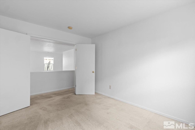 carpeted spare room featuring baseboards