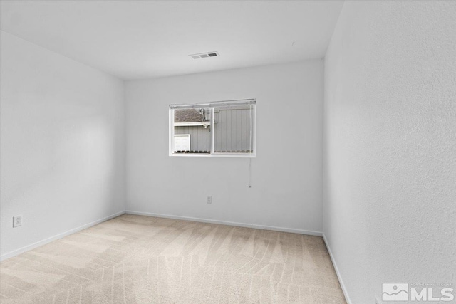 carpeted spare room with visible vents and baseboards