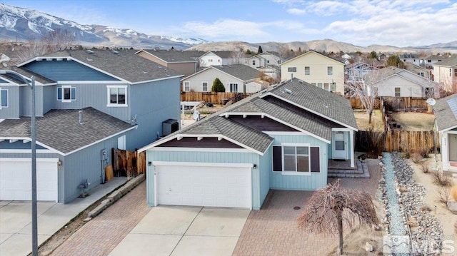 view of front facade with a mountain view, driveway, fence, and a residential view