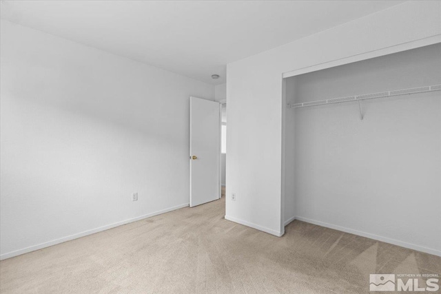 unfurnished bedroom featuring carpet floors, a closet, and baseboards