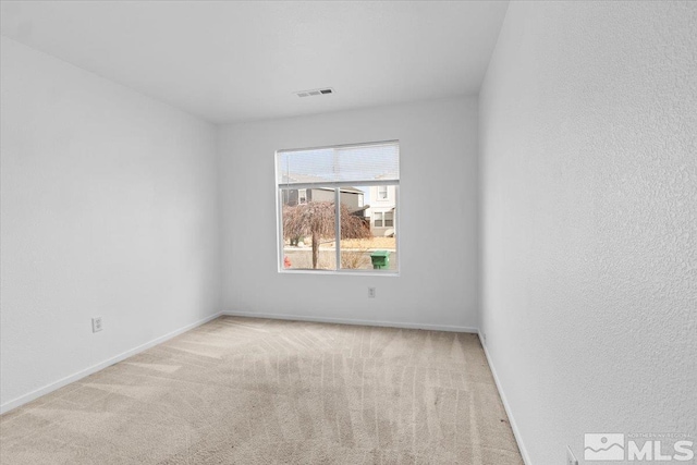 empty room with carpet, visible vents, and baseboards