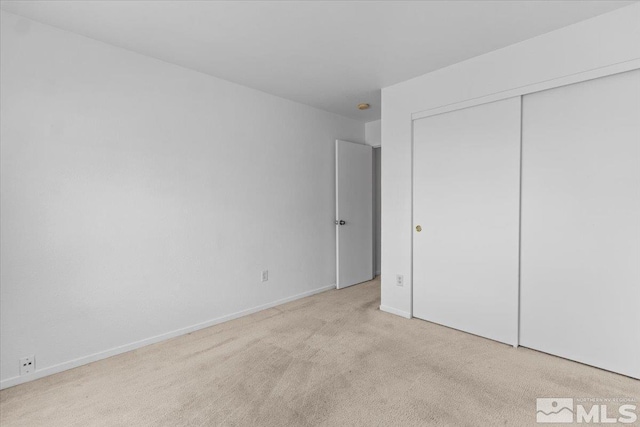 unfurnished bedroom with carpet floors, a closet, and baseboards