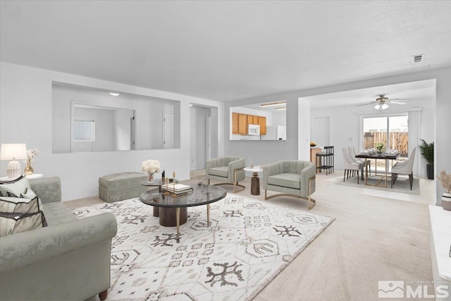 carpeted living area featuring visible vents and ceiling fan