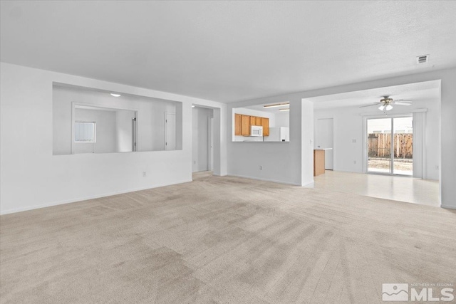 unfurnished living room with a ceiling fan, visible vents, and light colored carpet