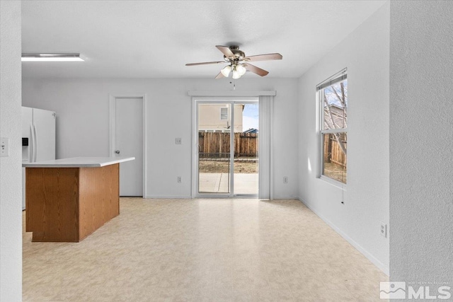 unfurnished living room with baseboards, ceiling fan, and light floors