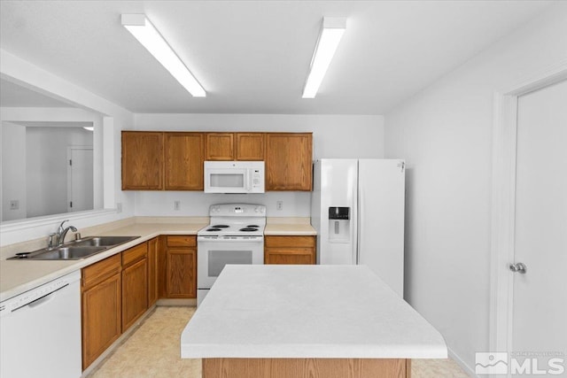 kitchen with brown cabinets, light countertops, a kitchen island, a sink, and white appliances