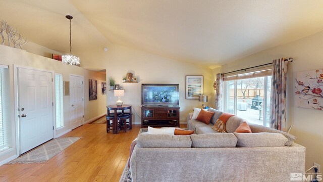 living area featuring light wood-type flooring, baseboards, and vaulted ceiling