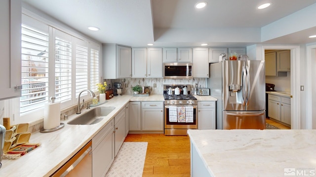 kitchen with recessed lighting, decorative backsplash, appliances with stainless steel finishes, light wood-style floors, and a sink