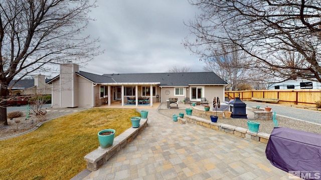 back of property with an outdoor fire pit, a patio area, fence, and a lawn