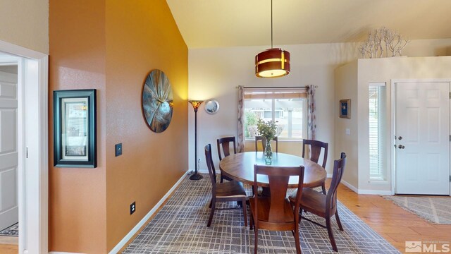 dining space featuring vaulted ceiling, baseboards, and wood finished floors