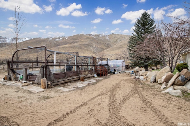 view of yard featuring an outbuilding, a greenhouse, a vegetable garden, and a mountain view