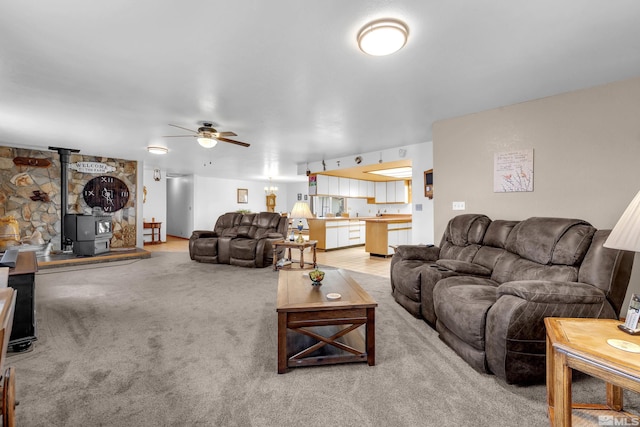 living room with light carpet, a wood stove, and a ceiling fan