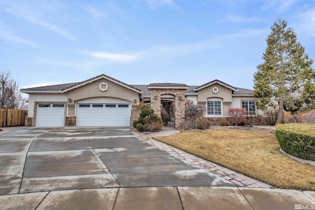 mediterranean / spanish-style home with driveway, stone siding, an attached garage, and stucco siding