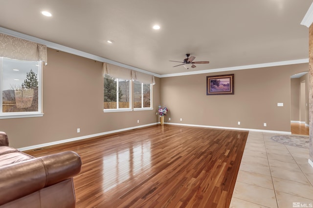 unfurnished living room featuring ceiling fan, ornamental molding, light wood finished floors, and baseboards