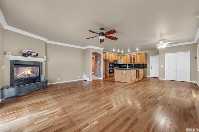 unfurnished living room featuring ornamental molding, baseboards, a fireplace, and light wood finished floors