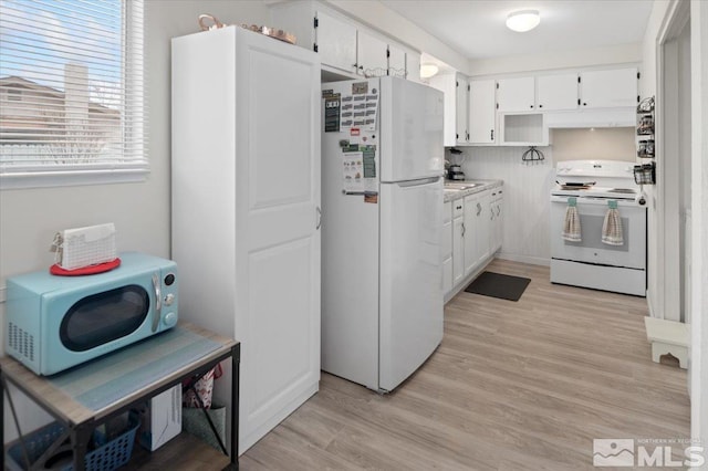 kitchen with white appliances, light countertops, light wood-style floors, white cabinetry, and a sink